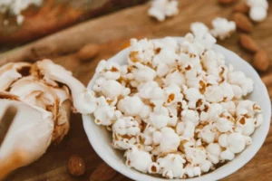 Close-up of a bowl filled with freshly popped homemade popcorn on a wooden surface.